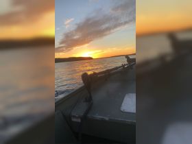 A serene sunset view from the bow of a boat, showcasing the tranquil waters and vibrant sky — perfect for evening cruises.
