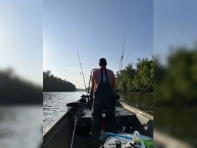 A fisherman prepares for a day on the water, surrounded by fishing gear and the serene beauty of nature — perfect for outdoor enthusiasts and fishing trips.