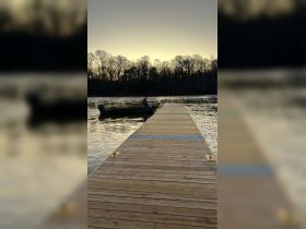 A serene view of a dock leading to a boat at sunset, perfect for fishing or leisurely outings on the water.