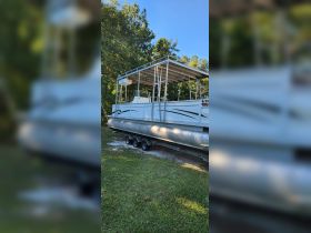 A side view of a pontoon boat docked on land, showcasing its spacious design and structure, perfect for leisurely outings on the water.