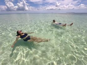 A couple enjoys a relaxing float in the crystal-clear waters, perfect for a serene beach day or romantic getaway.