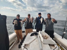 A group of friends proudly displays their catch after a successful fishing trip, showcasing the joy of fishing on the open water.