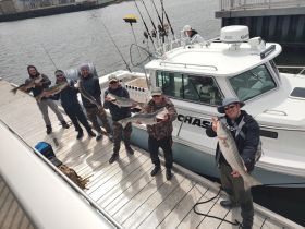 A group of friends proudly displays their catch after a successful fishing trip, showcasing camaraderie and the thrill of the catch aboard their boat.
