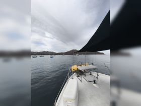A serene view of a boat's deck with a scenic backdrop of calm waters and distant hills, perfect for exploring coastal destinations.