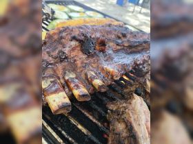 Deliciously grilled ribs and vegetables on the barbecue, perfect for onboard dining experiences during a boat trip.