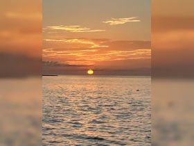 A stunning sunset over calm waters, creating a picturesque backdrop perfect for evening boat cruises.
