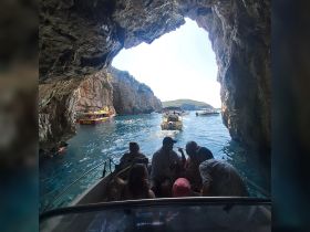 A lively group enjoys a boat ride through a scenic cave, surrounded by stunning rock formations and other boats, capturing the essence of adventure on the water.