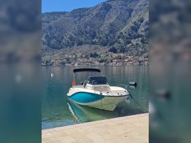 A sleek speedboat docked in calm waters, surrounded by stunning mountainous scenery — perfect for exploring the beautiful coastline.