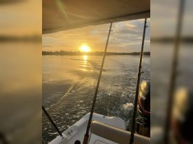 A serene sunset view from the back of a boat, showcasing the tranquil waters and the fading light — perfect for evening cruises.