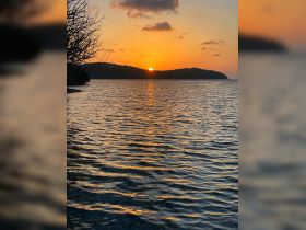 A stunning sunset over the tranquil waters, highlighting the serene coastline — perfect for capturing the beauty of nature during a boat trip.