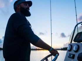 A man enjoys a serene fishing experience at sunset, showcasing the perfect blend of relaxation and adventure on the water.