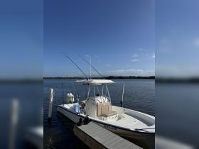 A sleek speedboat docked at the pier, ready for a day of fishing on calm waters under a clear blue sky.