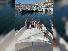 A cheerful group waves from the bow of a boat at the marina, capturing a joyful moment perfect for family outings or group adventures on the water.
