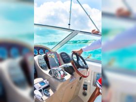 A close-up view of the helm and console of a boat, showcasing the steering wheel and controls, perfect for those interested in boating experiences.