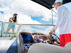 A joyful celebration on a boat as a graduate enjoys the moment with a drink, showcasing the perfect backdrop for memorable parties on the water.