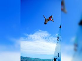 A thrilling moment captured as a person jumps off a boat into the clear blue waters, showcasing the excitement of summer adventures on the water.