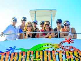 A lively group of friends enjoys a boat party, celebrating with drinks and smiles aboard the Margaritaville vessel — perfect for unforgettable outings on the water.