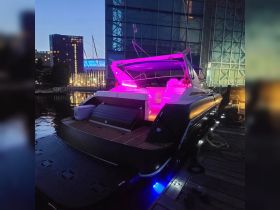 A sleek yacht docked at night, illuminated with vibrant lighting, showcasing its modern design and ambiance — perfect for evening cruises or private events.