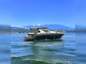 A sleek yacht cruising through clear waters with a stunning mountain backdrop, perfect for luxury outings and scenic adventures.