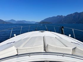 A stunning view from the front deck of a yacht, showcasing the serene waters and majestic mountains in the background — perfect for a day of relaxation on the water.