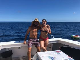 A couple poses happily on the deck of a boat, enjoying a sunny day on the ocean — perfect for romantic getaways or fun adventures at sea.