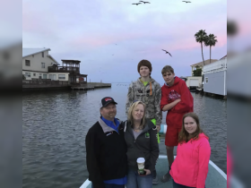 A family poses together on a boat during sunset, capturing a memorable moment on the water with a scenic backdrop.