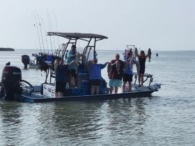 A group of friends proudly displays their fishing catch while aboard a boat, celebrating a successful day on the water.