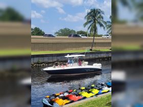 A lively group enjoys a day on the water aboard a Scarab boat, with colorful jet skis lined up nearby, perfect for thrilling water activities.