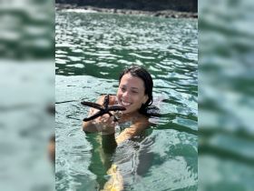A joyful swimmer holds a starfish in the water, showcasing a delightful marine encounter — perfect for ocean lovers and wildlife enthusiasts.