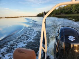 A scenic view from the back of a Pioneer boat cruising through calm waters, showcasing the beautiful reflections and serene landscape.