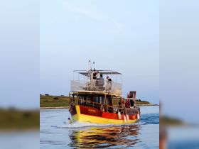 A lively group enjoys a scenic boat ride aboard the 'Sandra,' showcasing the beauty of the water and the camaraderie of friends on an adventure.