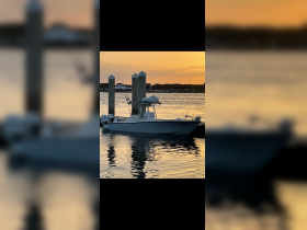 A serene view of a speedboat docked at sunset, reflecting the warm colors of the sky on the water — perfect for evening cruises.