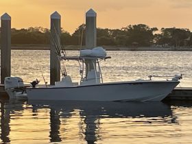 A sleek boat docked at sunset, reflecting the warm hues of the water — perfect for fishing or leisure outings.