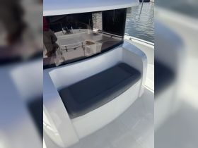 A cozy seating area inside a boat, featuring a comfortable cushion and a view of the helm, perfect for relaxing while cruising.