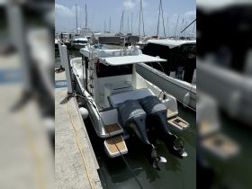 A detailed view of a center console boat docked at the marina, showcasing its sleek design and twin Yamaha outboard motors.