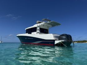 A striking view of a Barracuda boat anchored in clear turquoise waters, showcasing its sleek design against a vibrant blue sky.