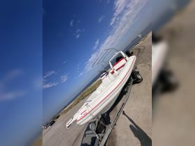 A sleek speedboat is docked and ready for adventure, showcasing its vibrant design against a clear blue sky.