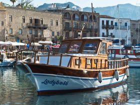 A beautifully crafted wooden boat named 'Ladyboss' docked in a picturesque harbor, showcasing the charm of coastal boating.