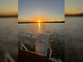 A serene sunset view from the back of a boat, showcasing the tranquil waters and the silhouette of the landscape — perfect for peaceful evening cruises.