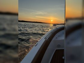 A stunning sunset view from the deck of a boat, showcasing the tranquil waters and the silhouette of the horizon — perfect for evening cruises.