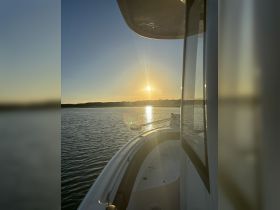 A serene sunset view from the bow of a boat, showcasing the tranquil waters and the fading light of day — perfect for evening cruises.