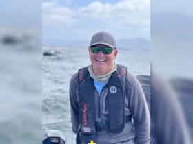 A smiling man wearing a life jacket enjoys a day on the water, showcasing the excitement of boating adventures.
