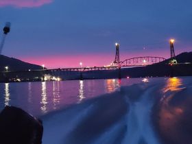 A stunning sunset view over a bridge, reflecting beautifully on the water — a perfect moment captured during a boat ride.