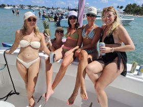 A lively group of friends enjoys a fun day on the boat, celebrating with drinks and laughter in a vibrant waterfront setting.