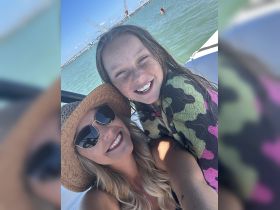 A joyful moment captured with a smiling woman and a girl enjoying a sunny day on the water, perfect for family outings and summer adventures.