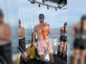 A group of friends celebrates a successful fishing trip, showcasing a vibrant catch against the backdrop of the open ocean. Perfect for fishing enthusiasts and adventure seekers.
