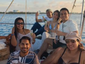 A lively group enjoys a celebration aboard a yacht, raising glasses and sharing smiles against a beautiful water backdrop.