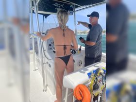 A woman at the helm of a boat receives instructions from a companion, showcasing the excitement of navigating the waters together.