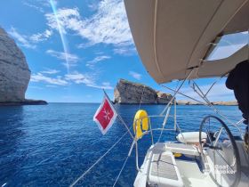A picturesque view from a sailboat navigating through stunning coastal cliffs under a bright blue sky, showcasing the beauty of the open water.