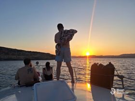 A group of friends enjoys a stunning sunset from the deck of a boat, creating a perfect backdrop for memorable moments on the water.